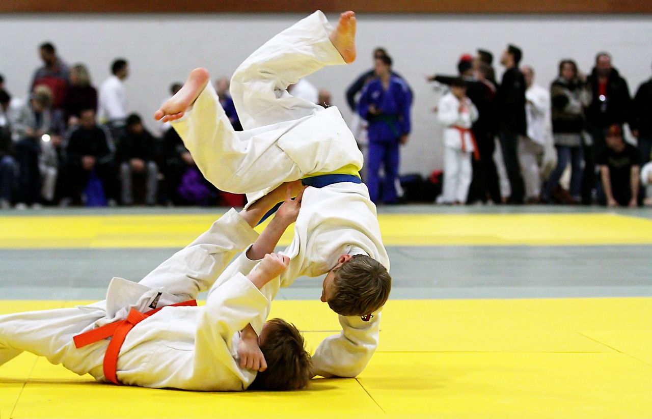 A junior judoka is thrown head over heels onto the mat at a tournament