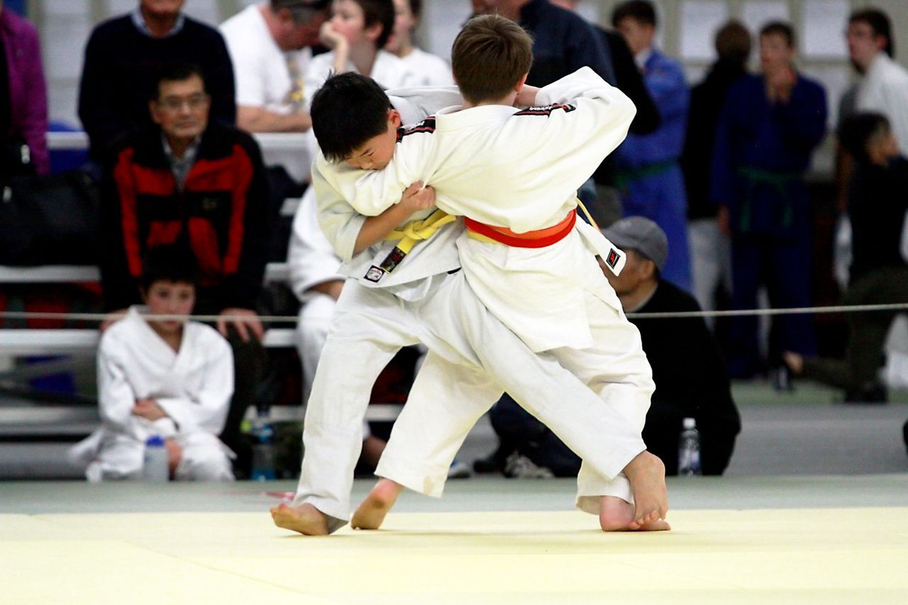 Two junior judoka grip each other's jackets during a tournament match